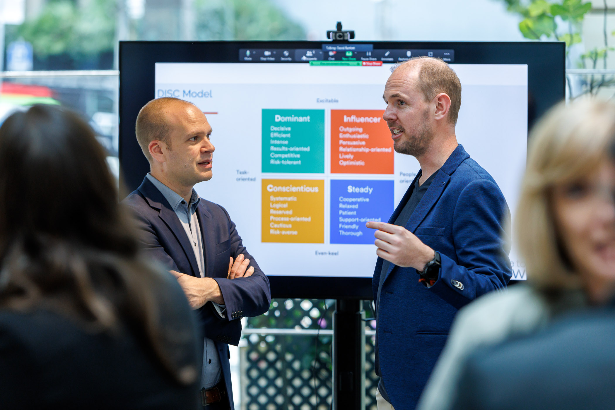 Two-person discussion in front of a DISC model screen at a workshop